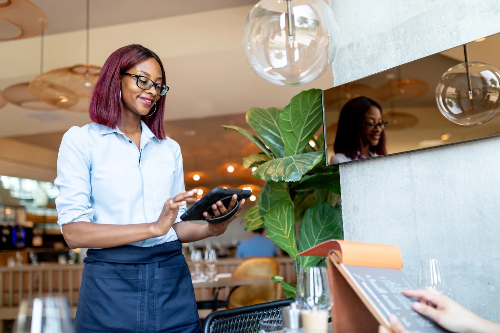 Personal nimmt Bestellung mit mobiler Kasse von Lightspeed am Tisch auf