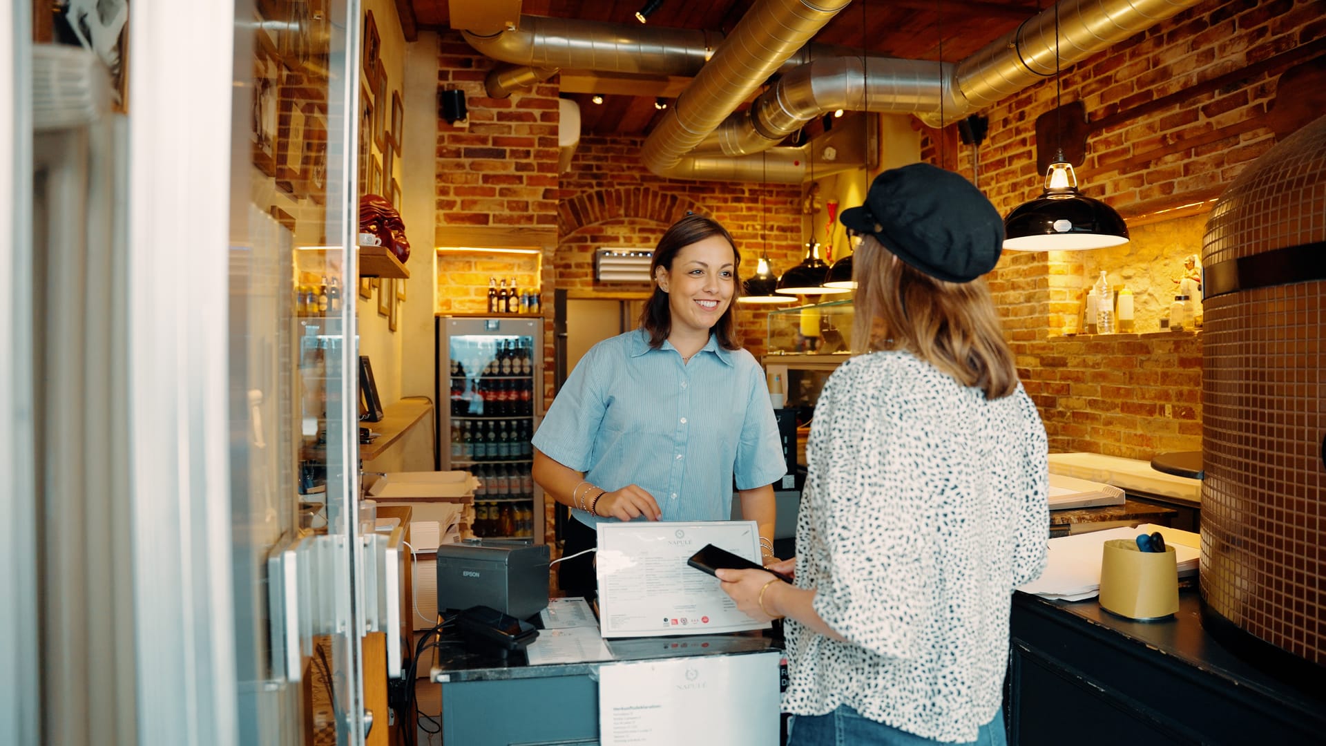 Kundin bezahlt mit dem Smartphone im Napulé Takeaway. Kassensystem von Lightspeed und Vendomat.